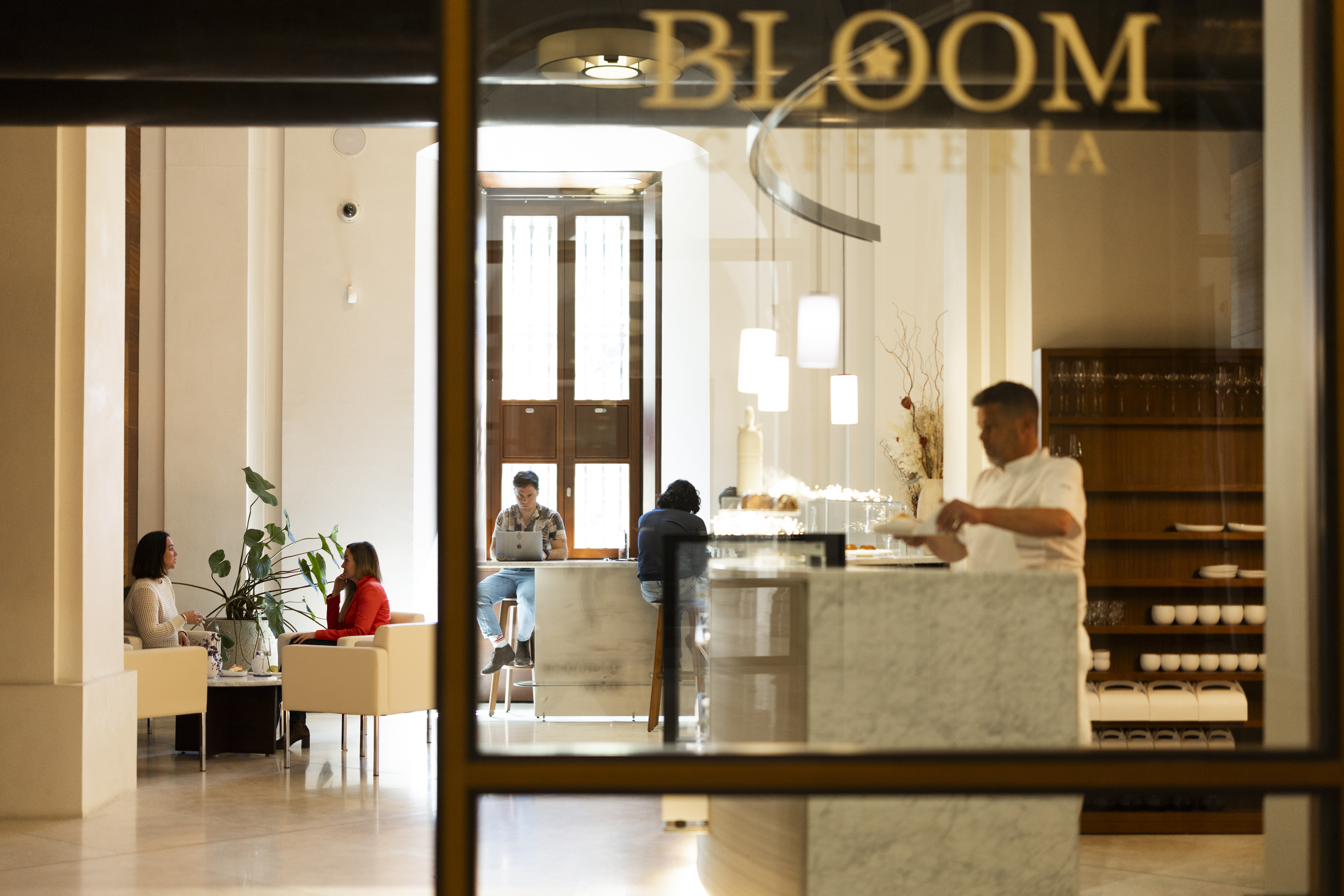 Vista desde la entrada de Bloom Cafetería con el letrero dorado