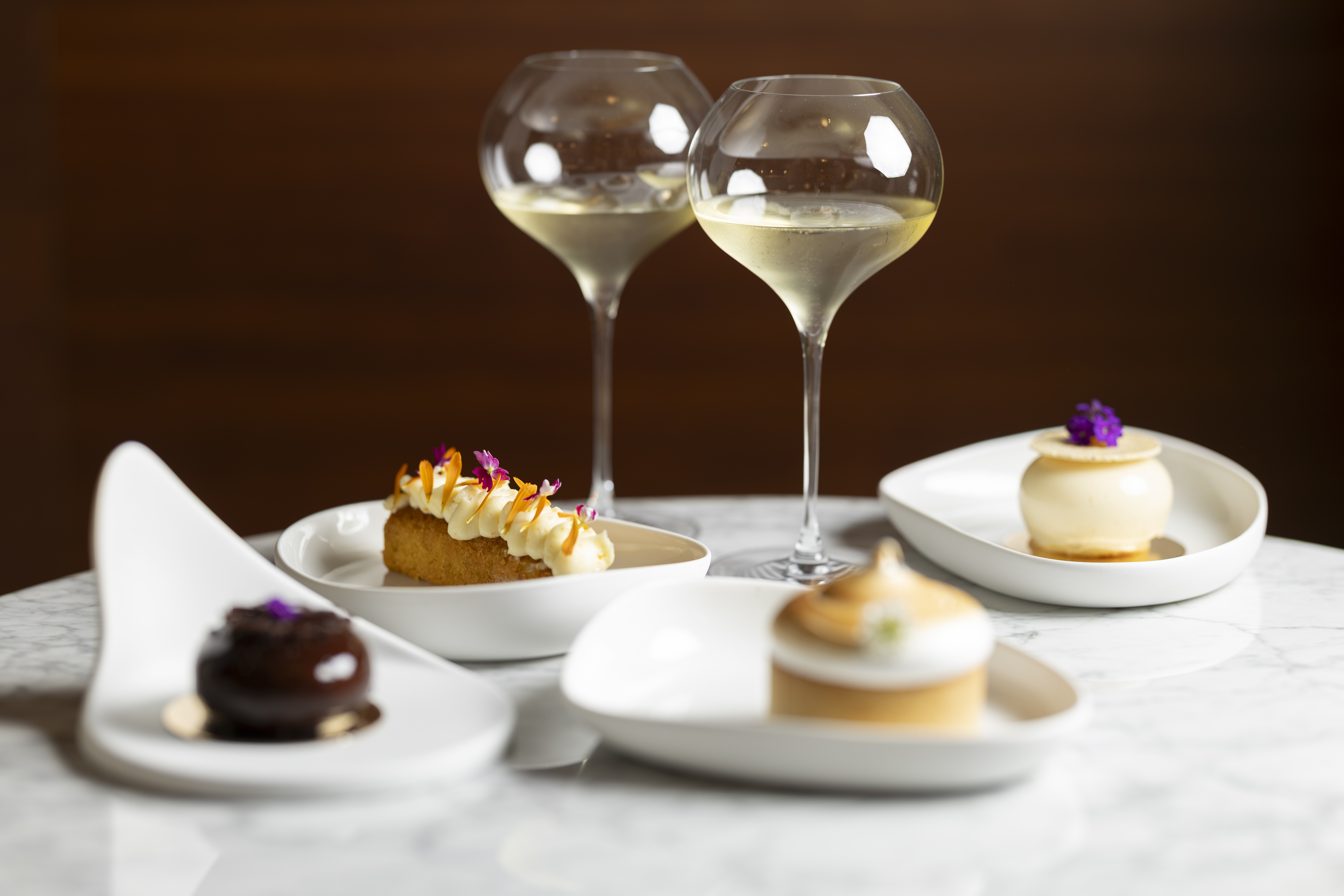 Dos copas de vino con pasteles sobre mesa de mármol