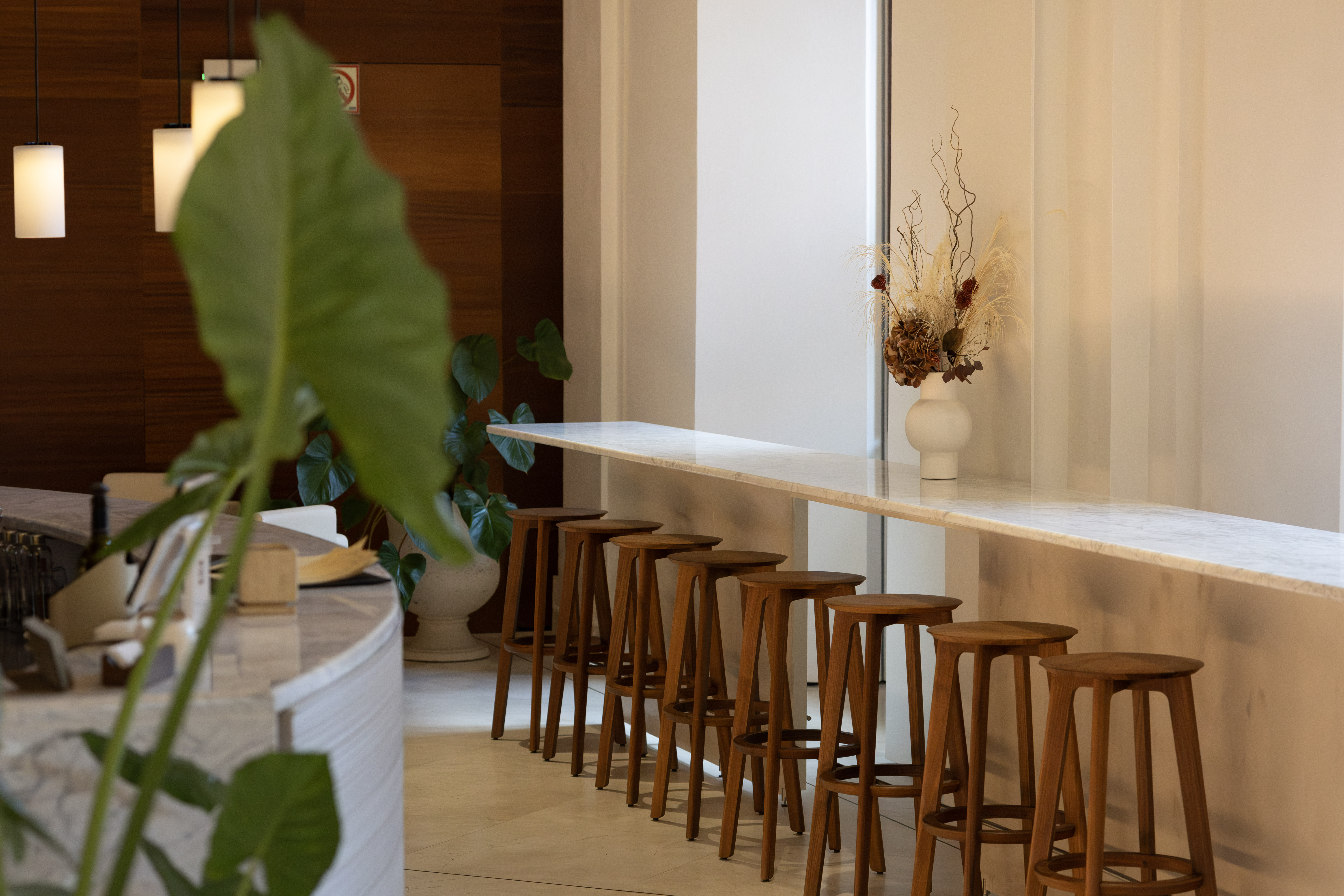 Barra alta con taburetes de madera y mostrador de mármol